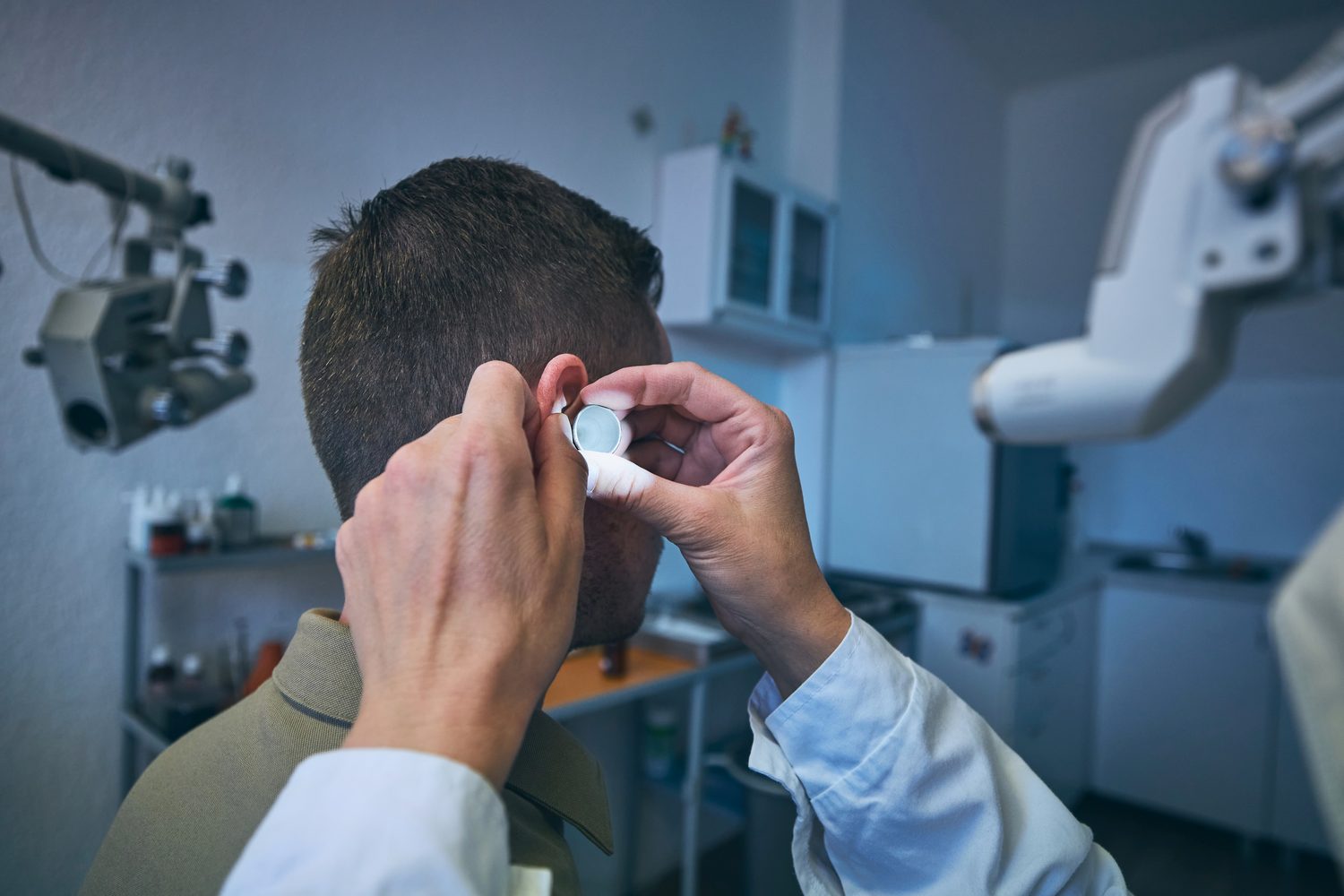 Specialist examining a patient's ear canal with an otoscope in an ENT clinic
